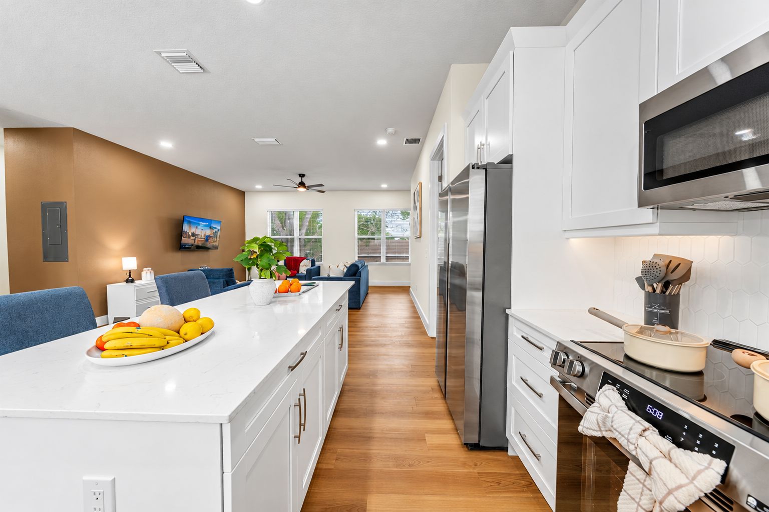 A modern kitchen with white cabinetry, a stainless steel refrigerator, and a built-in oven.