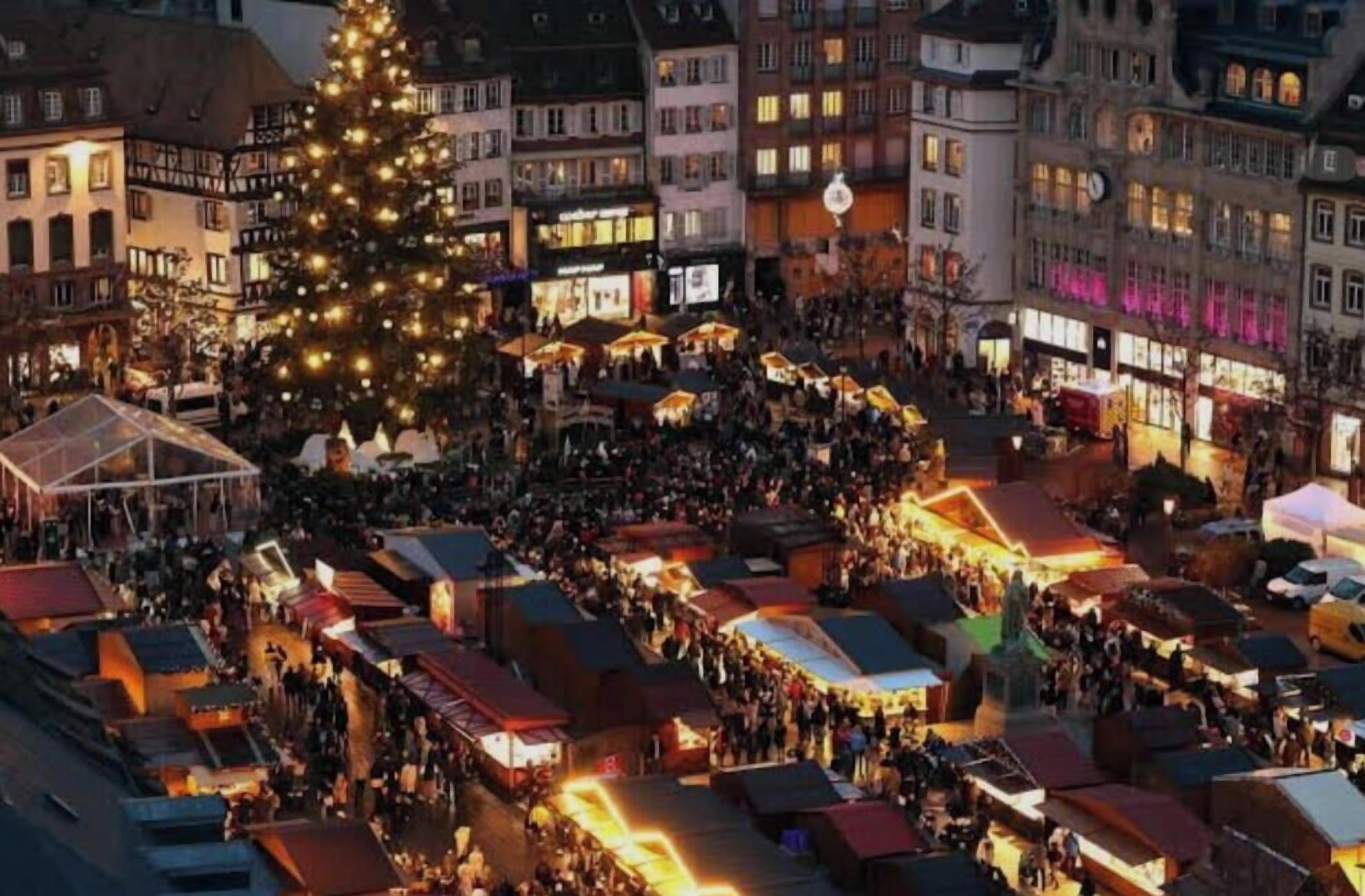 A crowded market with stalls and a large Christmas tree.