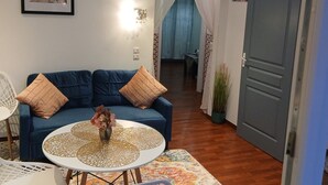 A living room with a blue sofa, a round coffee table, a chandelier, and a framed picture on the wall.