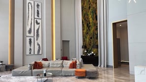 Een moderne woonkamer met een hoekbank, poefs, een salontafel en abstracte muurkunst.