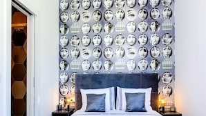 Una habitación de hotel moderna con una cama grande, dos mesitas de noche y una pared decorada con numerosos retratos circulares.