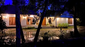 Ein Haus mit Veranda, Blumentöpfen und einem kleinen Teich.