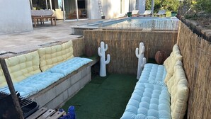 Ein Poolbereich mit integriertem Sitzbereich, einer Kakteendekoration und einem Bambuszaun.