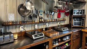 Una cocina con electrodomésticos de acero inoxidable, ollas colgantes y una variedad de especias en estantes.