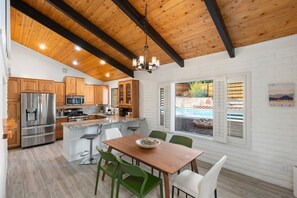 Eine moderne Küche mit Holzschränken, einem Edelstahlkühlschrank und einem Essbereich mit Holztisch und -stühlen.