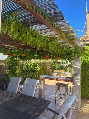 An outdoor patio with a pergola, seating, and a table.