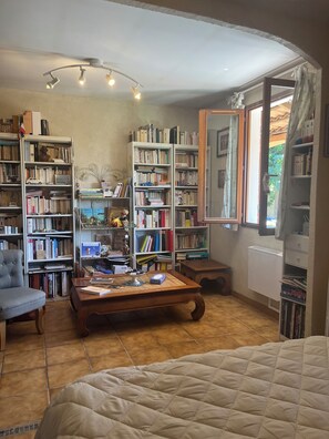 A room with a bed, a desk, a bookshelf, and a window with curtains.