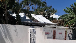 A rectangular swimming pool with clear blue water, surrounded by a low wall and palm trees. - T2 furnished with terrace and pool - Saint-Louis 🌺. 🌴 (Saint-Louis)