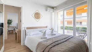 Een hotelkamer met een bed, een bureau en een stoel, een zithoek en een balkon met uitzicht.