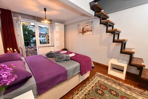 Una camera da letto con un letto, una finestra con tende, una scala e vista sugli edifici esterni.