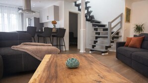 Een moderne woonkamer met een houten salontafel, een bank en een trap.