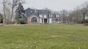 Een groot huis met een ruime tuin, een groot raam en een schoorsteen.