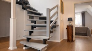 Een moderne trap met een minimalistisch ontwerp, een houten vloer en een bed in de aangrenzende kamer.
