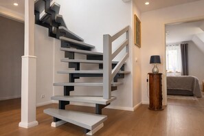 A modern staircase with a minimalist design, a wooden floor, and a bed in the adjacent room. - Fitters' apartment Drei Eichen, Sorthum 42, 27639 Wurster North Sea coast (Wurster Nordseeküste)