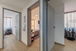 Habitació d'hotel amb llit, escriptori i cadira. Hi ha una porta que dóna a una altra habitació.