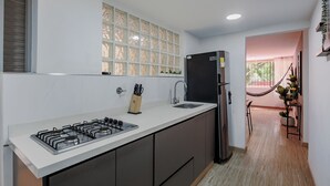 A modern kitchen with a gas stove, a black refrigerator, and a window with decorative glass panels. - Perfect 3-bedroom apartment in Medellín for a relaxing stay (Medellín)