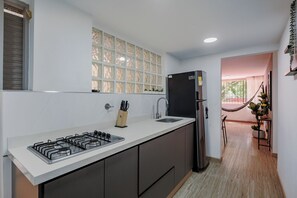 Cuina moderna amb forlla de gas, nevera negra i finestra amb panells de vidre decoratius.