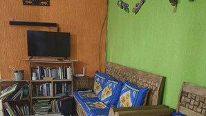 Een woonkamer met een bank, een televisie en een boekenkast.