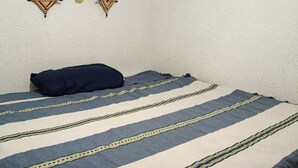 Een kamer met een bed, een wanddecoratie en een raam.