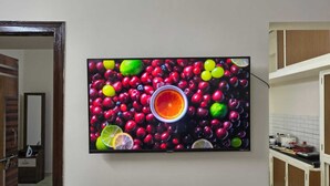 Una televisione a parete mostra una composizione colorata di frutta.