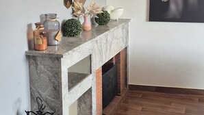 Una chimenea de mármol con revestimiento de ladrillo, un adorno mural geométrico y una obra de arte enmarcada encima.