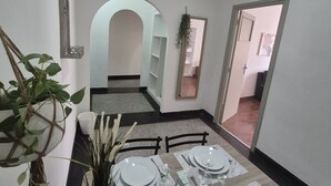 Un comedor con una mesa preparada para cuatro, paredes blancas y un espejo en la pared.
