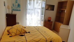 Een slaapkamer met een bed, nachtkastje, dressoir en kast.