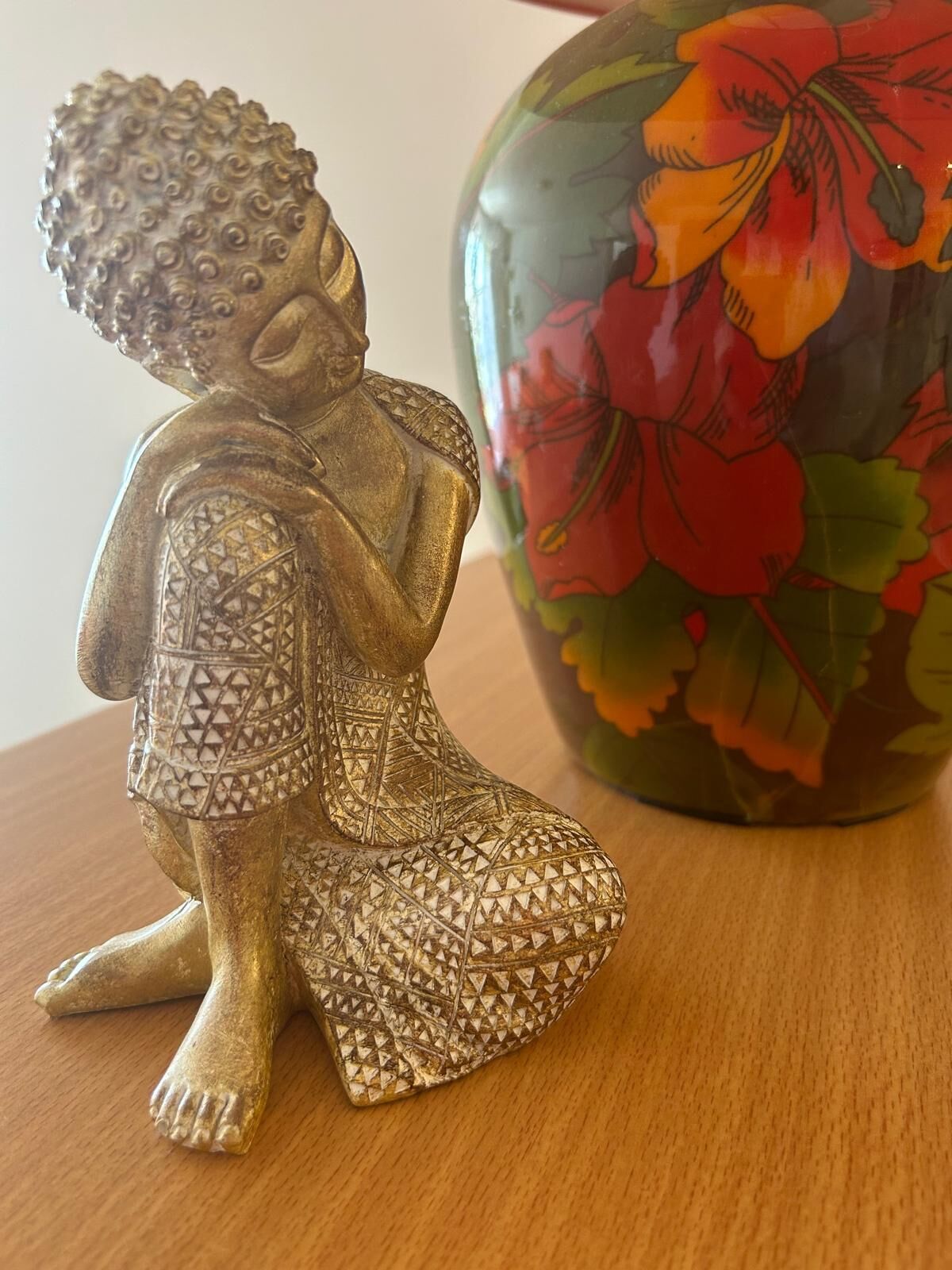 Une statue de Bouddha ornée de motifs complexes sur une surface en bois.