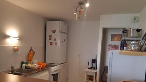 Een keuken met een koelkast, gootsteen en een tafeltje met een mand.