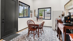 A dining area with a table, chairs, a rug, and a kitchen counter with appliances. - Riverside Retreat! Quiet and Charming 2 bed/2 bath (New Orleans)