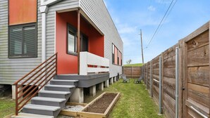 A residential property with a staircase leading to a porch, a fenced backyard, and a raised garden bed. - Riverside Retreat! Quiet and Charming 2 bed/2 bath (New Orleans)