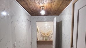 A narrow hallway with wooden flooring, white walls with marble-like patterns, and a door with a towel hanging on it.