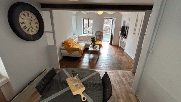A modern living space with a dining table, sofa, and kitchen area. - Room in a house 5 minutes from Lac du Bouchet (Cayres)