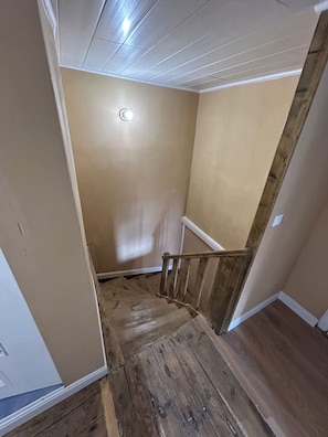 Una escalera de madera con peldaños que conducen a una plataforma, paredes color beige y techo blanco.