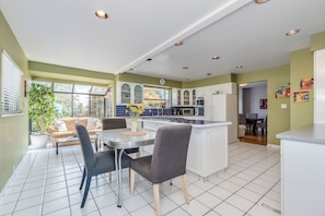 Une cuisine moderne avec des meubles blancs, un îlot central et un coin repas comprenant une table et des chaises.