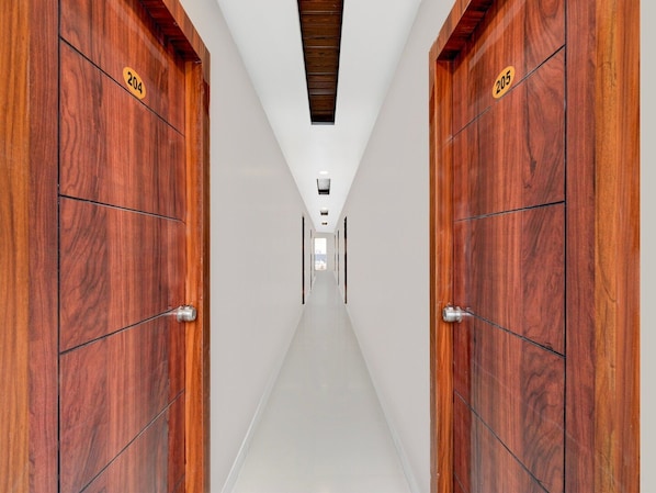 A hallway with wooden doors labeled 204 and 205, leading to a room with a white ceiling and a small window.