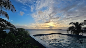 Una piscina con vista al océano y al cielo al atardecer.
