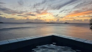 Ein Pool mit Blick auf das Meer und ferne Inseln im Sonnenuntergang.