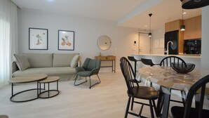 Un salon moderne avec un canapé, une table ronde et des chaises. Il y a également un coin cuisine avec des placards et un évier.