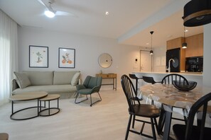 A modern living room with a sofa, a round table, and chairs. There is a kitchen area with cabinets and a sink. - Los Colibries 2001 - Two Bedroom Apartment, Sleeps 5 (Punta del moral)