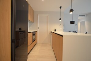 A modern kitchen with wooden cabinets, a stainless steel refrigerator, and pendant lighting. - Los Colibries 2001 - Two Bedroom Apartment, Sleeps 5 (Punta del moral)