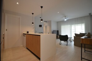 A modern kitchen with a central island, a dining area with a sofa and chairs, and a living room with a TV and curtains. - Los Colibries 2001 - Two Bedroom Apartment, Sleeps 5 (Punta del moral)
