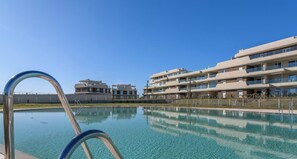 Ein Swimmingpool mit klarem, blauem Wasser, umgeben von modernen Mehrstöckern mit Balkonen.