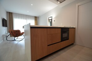 Eine moderne Küche mit einer Holztischinsel, einem eingebauten Ofen und einem Stuhl.