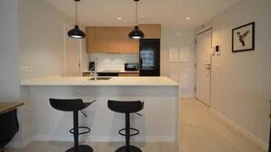 Ett modernt kök med två hänglampor, en vit bänkskiva och två svarta barstolar.