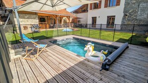 Un terrazzo in legno con piscina, unicorni gonfiabili e una zona salotto coperta.