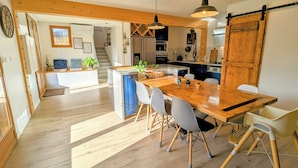 Una cucina moderna con travi in legno, un'isola grande e una zona pranzo con tavolo e sedie in legno.