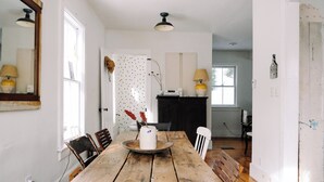 Un comedor con una mesa de madera, sillas, un florero con flores y una chimenea.
