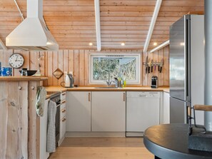 A modern kitchen with wooden walls, a window with a view, a stainless steel refrigerator, and a kettle on the counter. - "Elenor" - 1.3km from the sea by Interhome (Græsted)