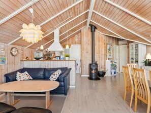 A cozy cabin interior with a sofa, dining table, wooden floors, a kitchen area, and a wood-burning stove. - "Elenor" - 1.3km from the sea by Interhome (Græsted)